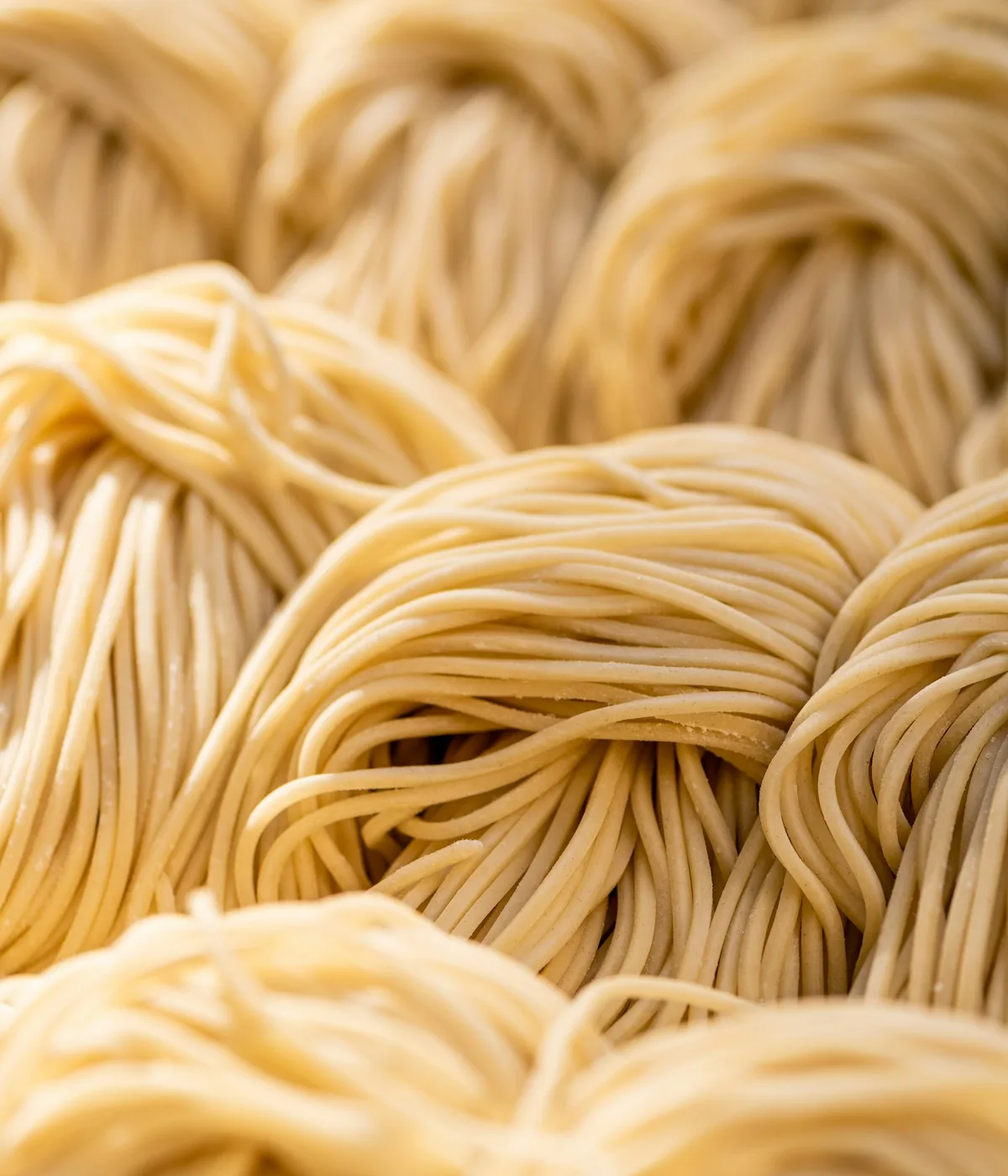 Nidi di pasta fresca su un piano di lavoro. Fotografia d’ispirazione, non il menù di un host reale.