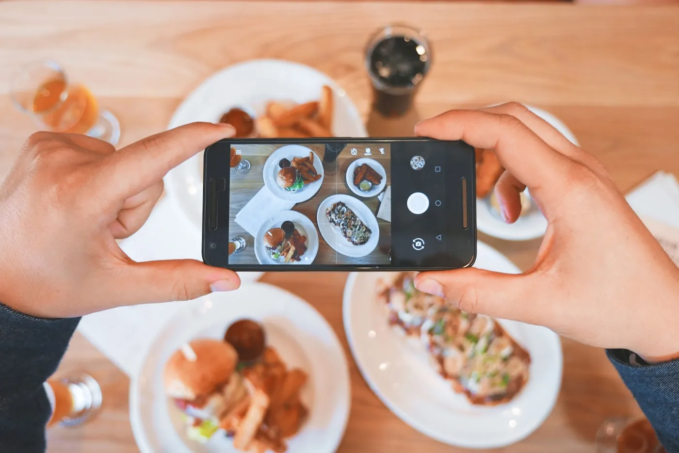 Mani che fotografano dei piatti con uno smartphone. Fotografia d’ispirazione.